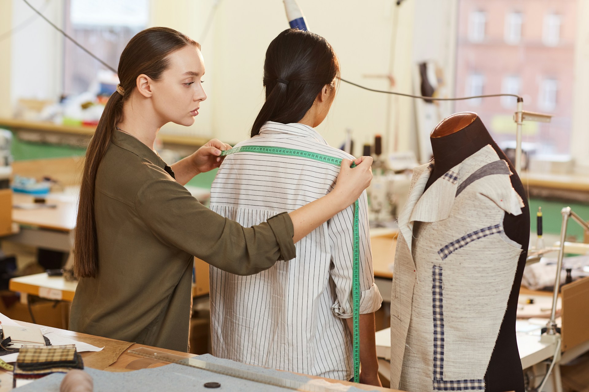 a retailer takes measurements of a customer trying on a button down dress shirt to assess how the garment fits the customer's body structure, which catecut is trying to replicate with its digital styling solution for online retailers and fashion marketplaces.